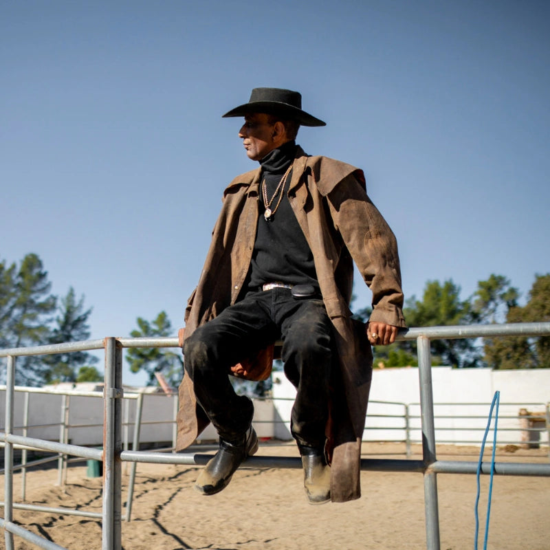 Homme portant des santiags dans un ranch avec un chapeau de cowboy et une ceinture de cowboy